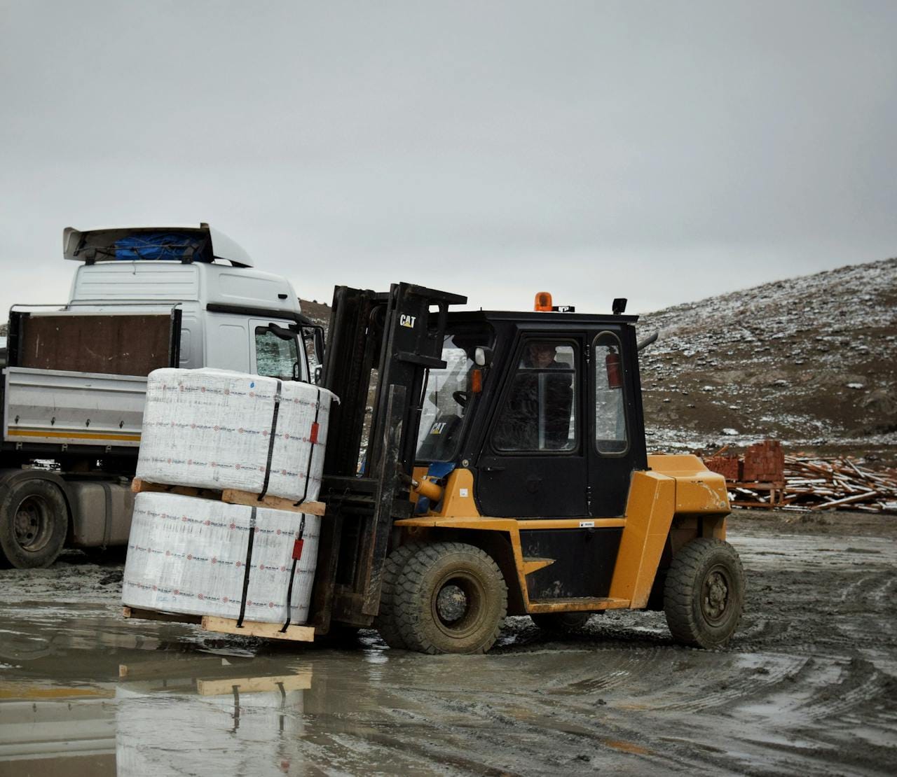 Forklift transporting large pallet in an outdoor industrial setting.